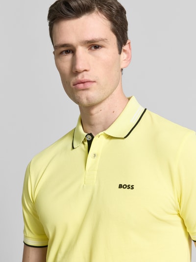 Männermodel trägt Slim Fit Poloshirt aus reiner Baumwolle Modell 'PAUL' von BOSS Green, Optik: Unifarben, Label-Print, Nahaufnahme Oberkörper.