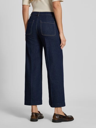 Frauenmodel trägt Wide Fit Jeans aus Baumwoll-Mix Modell 'Jessie' von MANGO, dunkelblau, sichtbare Nähte, aufgesetzte Taschen, Ganzkörperansicht Rückansicht.