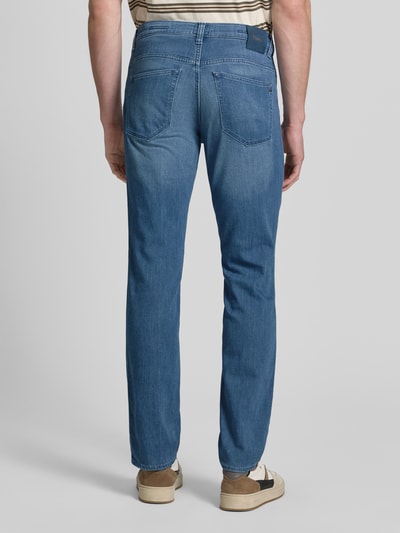 Männermodel trägt Regular Fit Jeans aus Baumwoll-Mix mit Viskose-Seiden-Anteil Modell 'Chuck' von Brax in Denim-Optik, 5-Pocket-Design, Label-Patch, Label-Prägung, Gürtelschlaufen, Twill-Materialverarbeitung, Ganzkörperansicht Rückansicht.
