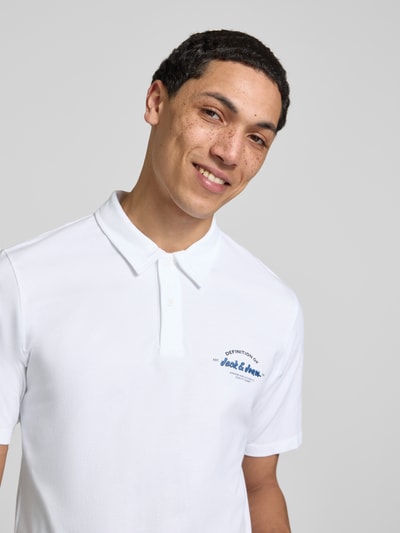 Männermodel trägt weißes Poloshirt mit Label-Print Modell 'BRANDON' von Jack & Jones, Reine Baumwolle, Regular-Fit, Nahaufnahme Oberkörper.