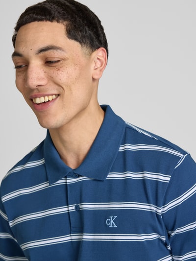 Männermodel trägt Regular Fit Poloshirt mit Logo-Stitching von Calvin Klein Jeans, Reine Baumwolle, Polokragen, Knopfleiste, Nahaufnahme Oberkörper.