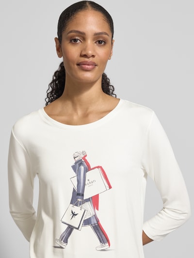Frauenmodel trägt Regular Fit Longsleeve aus Viskose-Mix mit Ziersteinbesatz von monari, Motiv-Print, Logo-Print, 7/8-Arm, Rundhalsausschnitt, elastischer Viskose-Mix mit Modal-Anteil, Rückenlänge bei Größe 36: 59 cm, Nahaufnahme Oberkörper.