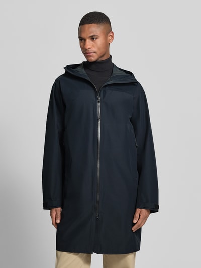 Männermodel trägt Regular Fit Mantel mit Logo-Detail Modell 'Treeline' von Peak Performance in dunklem Ton, Zweiwege-Reißverschluss, Kapuze, Eingrifftaschen, glatte Struktur, Ganzkörperansicht von vorne, Rückenlänge 97 cm, Schulterbreite 46 cm, Brustweite 60 cm, Ärmellänge 66 cm.