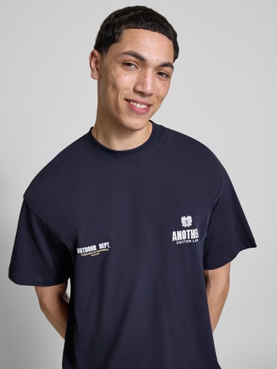 Männermodel trägt Regular Fit T-Shirt mit Logo-Print von ANOTHER COTTON LAB aus reiner Baumwolle, dunkelblau, Nahaufnahme Oberkörper.