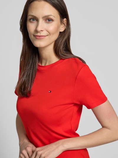 Modelka nosi Slim Fit T-Shirt aus reiner Baumwolle von Tommy Hilfiger, czerwony, gładki, jersey, logo, okrągły dekolt, krótki rękaw, zbliżenie na górną część ciała