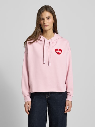 Frauenmodel trägt Hoodie mit Kapuze von Oui in Rosa aus Baumwoll-Mix, Lockerer-Schnitt, Tunnelzug, Label-Detail, gerippte Ärmelabschlüsse, Ganzkörperansicht von vorne.