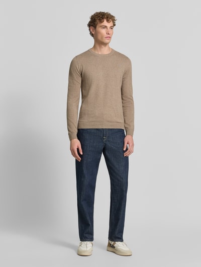 Männermodel trägt Regular Fit Pillover aus reiner Baumwolle von s.Oliver RED LABEL in Beige mit Struktur, kombiniert zu blauen Jeans, Ganzkörperansicht von vorne.