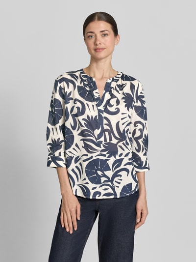 Modelka kobieca nosi Bluse mit Tunikakragen und 3/4-Arm od Oui z czystej bawełny, prosty krój, tunikowy kołnierz, zaokrąglony dół, długość tyłu 60 cm, długość rękawa 42 cm, wzór w granatowe i kremowe roślinne kształty, widok całej sylwetki z przodu.