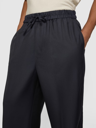 Männermodel trägt Stoffhose aus Woll-Mix von Officine Générale in Dunkelblau mit elastischem Bund und Tunnelzug, Nahaufnahme Oberkörper.