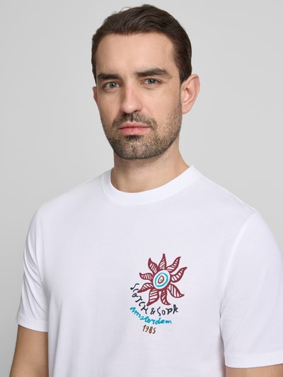Männermodel trägt weißes T-Shirt mit Label-Print und Rundhalsausschnitt von Scotch & Soda, Reine Baumwolle, Regular-Fit, Nahaufnahme Oberkörper.