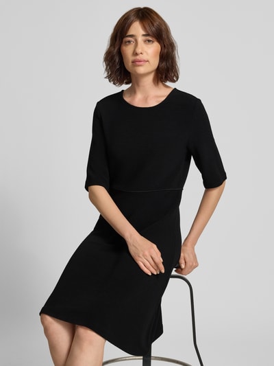 Frauenmodel trägt Minikleid aus Viskose-Mix mit Rundhalsausschnitt von Emporio Armani in Schwarz, taillierte Passform, Halbarm, Nahaufnahme Oberkörper.