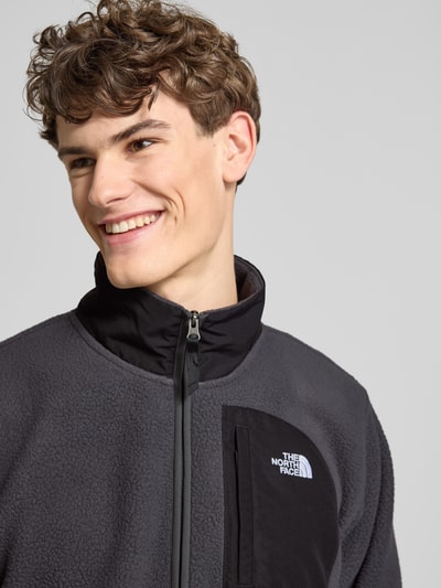 Männermodel trägt Fleecepullover mit Napoleontasche Modell 'YUMIORI' von The North Face in Dunkelgrau, Nahaufnahme Oberkörper.