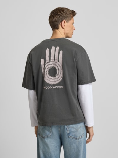 Männermodel trägt T-Shirt mit Rundhalsausschnitt Modell 'Gary' von Wood Wood, reine Baumwolle, relaxed Fit, Rückansicht, Ganzkörperansicht.