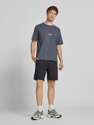 Mannenmodel draagt Regular Fit T-shirt met logoprint model 'Soho' van Jack & Jones, puur katoen, regular fit, ruglengte maat M 61 cm, geheellichaamsvooraanzicht.