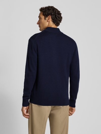 Männermodel trägt Strickpullover aus reiner Lammwolle mit Logo-Patch Modell 'Tay' von Wood Wood, marineblau, Regular Fit, Rückansicht, Ganzkörperansicht Rückansicht.