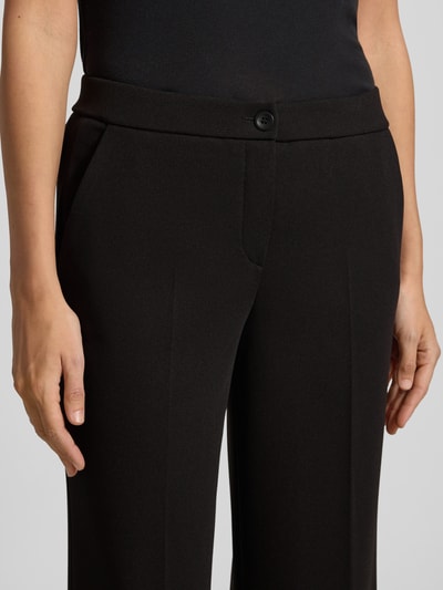Frauenmodel trägt Hose mit Bügelfalten Modell 'Hillda' von STEHMANN, Schwarz, weiter Schnitt, Material-Mix mit Stretch, Nahaufnahme Oberkörper.