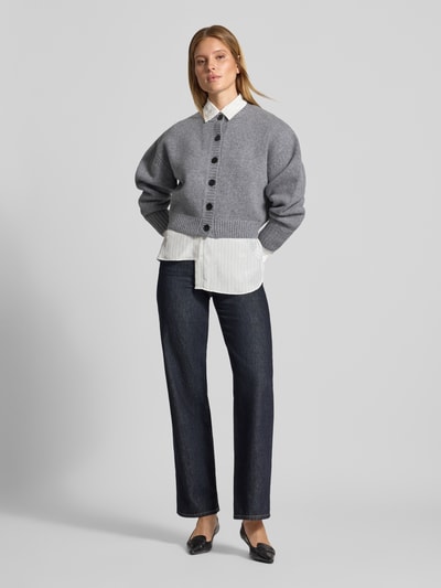 Vrouwenmodel draagt Knit Cardigan aus Wolle van Style Icon Collection in grijs met zwarte knoopsluiting, ribboorden, puur katoen, los model, ruglengte maat S 46 cm, mouwlengte maat S 58 cm, full body vooraanzicht.