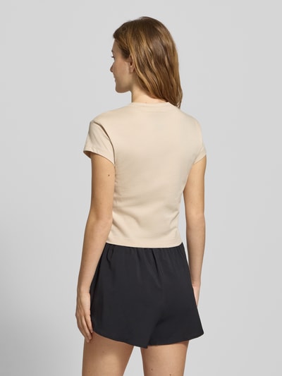Modelka nosi Cropped T-Shirt mit Label-Print od adidas Sportswear, kremowy kolor, bawełna, krój slim fit, długość tyłu 45 cm, widok z tyłu całej sylwetki.