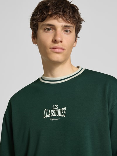 Männermodel trägt Boxy Fit T-Shirt aus reiner Baumwolle Modell 'LES' von Only & Sons, Optik: Unifarben, Label-Print, Jersey, Nahaufnahme Oberkörper.