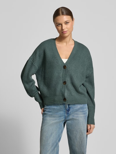 Modelka kobieca ma na sobie Relaxed Fit Strickjacke mit V-Ausschnitt Modell 'LEA' od Vero Moda, melanż, dzianina, widok całej sylwetki z przodu.