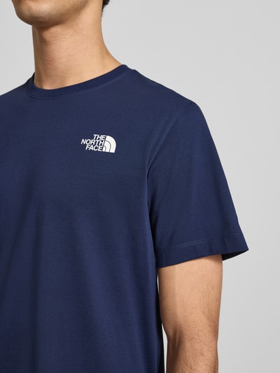 Männermodel trägt Regular Fit T-Shirt aus Baumwoll-Mix Modell 'EVOLUTION' von The North Face in Dunkelblau, Label-Detail, Nahaufnahme Oberkörper. Herren T-Shirt, Rundhalsausschnitt, Rückenlänge bei Größe M: 70 cm.