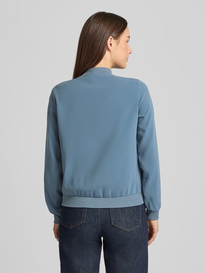 Młodzieżowy modelka nosi Regular Fit Bomberjacke mit College-Kragen Modell 'COCO' od Vero Moda, jednokolorowa, granatowa, długi rękaw, ściągacze, boczne kieszenie, widok całego ciała z tyłu.