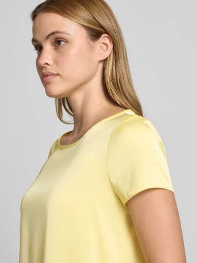 Frauenmodel trägt Blusenshirt mit Rundhalsausschnitt und abgerundetem Saum von Rinascimento in Gelb, Material-Mix, Nahaufnahme Oberkörper.