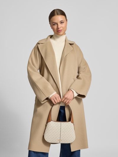 Frauenmodel trägt Shoulder Bag mit Allover-Logo-Print Modell 'Alice' von MICHAEL Michael Kors, beige, Logo-Applikation, Ganzkörperansicht von vorne. Szerokość w rozmiarze 1: 20 cm, długość 20 cm, głębokość 4 cm, długość paska na ramię 50 cm, główna komora z zamkiem, kieszeń wewnętrzna na zamek.