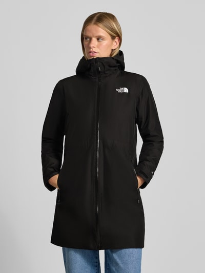 Modelka nosi czarną kurtkę z kapturem, zamek błyskawiczny dwustronny, kieszenie zapinane na zamek błyskawiczny, Model 'HIKESTELLER' od The North Face, krój regular fit, widoczne logo marki, długość tyłu w rozmiarze S: 86 cm, szerokość ramion: 41 cm, szerokość w rozmiarze S: 52 cm, długość rękawów: 65 cm, zdjęcie w całości od przodu.