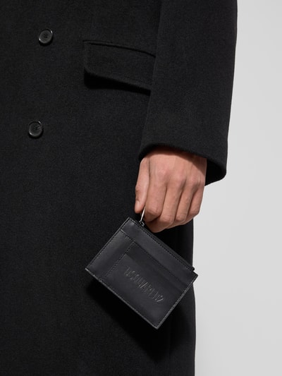 Männermodel trägt schwarzes Portemonnaie mit Label-Detail von Dsquared2 aus echtem, beschichtetem Leder, Nahaufnahme Hand.