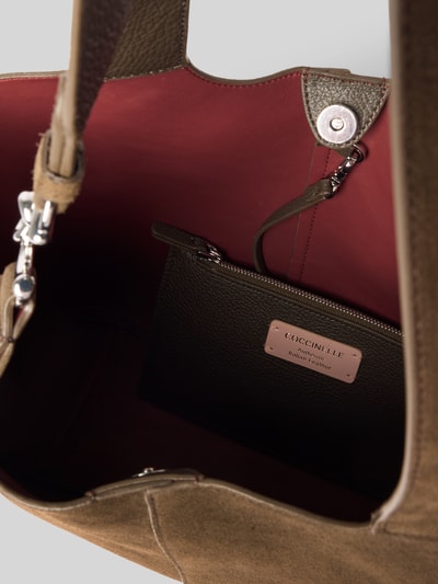 Produktfoto, Handtasche aus echtem Leder von Coccinelle mit rotem Innenfutter, herausnehmbarem Innenfach und Logo-Detail, Detailaufnahme