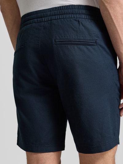 Männermodel trägt Shorts aus Leinen-Baumwoll-Mix Modell 'barton' von Matinique in Dunkelblau, Regular Fit, elastischer Bund, Tunnelzug, Detailaufnahme Rückansicht. Bundweite 43 cm, Innenbeinlänge 21 cm, Größe M.