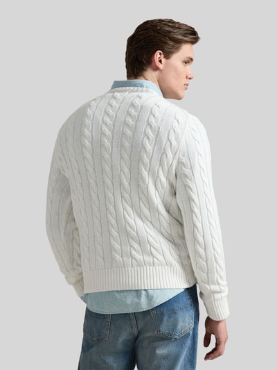 Männermodel trägt weißen Regular Fit Strickpullover aus reiner Baumwolle von Polo Ralph Lauren mit Zopfmuster, Rückansicht.