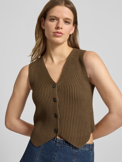 Frauenmodel trägt Shaped Fit Weste aus reiner Baumwolle von Marc O'Polo Denim in unifarbener Strickoptik mit Zopfmuster, Nahaufnahme Oberkörper.