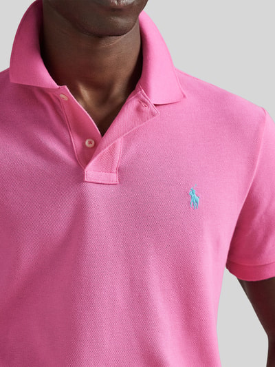 Männermodel trägt Regular Fit Poloshirt aus reiner Baumwolle von Polo Ralph Lauren in Pink, Piqué-Textur, Logo-Detail, Nahaufnahme Oberkörper.