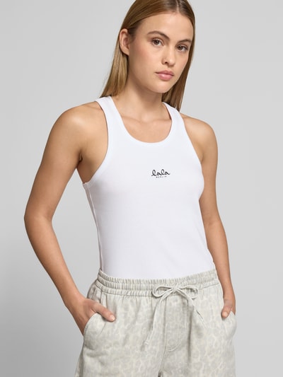 Frauenmodel trägt Tanktop mit Logo-Print von Lala Berlin aus elastischem Baumwoll-Mix mit körpernaher Passform, Weiß, Ripp-Optik, Rundhalsausschnitt, Ganzkörperansicht von vorne.
