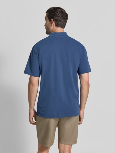 Męski model nosi Relaxed Fit Poloshirt mit Logo-Stitching od Scotch & Soda, bawełna, krój relaxed fit, krótki rękaw, Długość tyłu w rozmiarze M: 69 cm, Ganzkörperansicht Rückansicht.