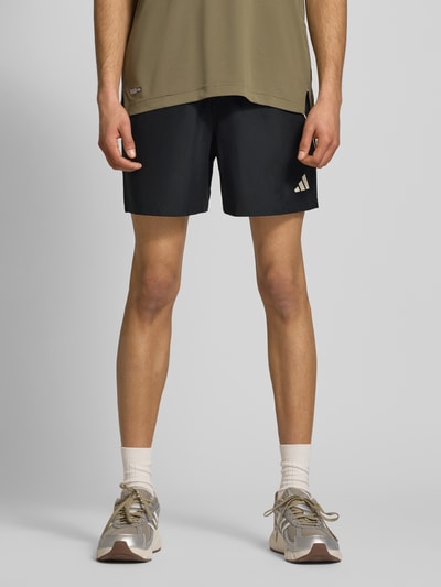 Männermodel trägt Regular Fit Sport-Shorts mit Kontraststreifen von adidas Sportswear, Optik: Unifarben, Passform: Regular-Fit, Logo-Print, Bundabschluss: elastisch mit Tunnelzug, Reißverschlusstaschen, Ganzkörperansicht von vorne.