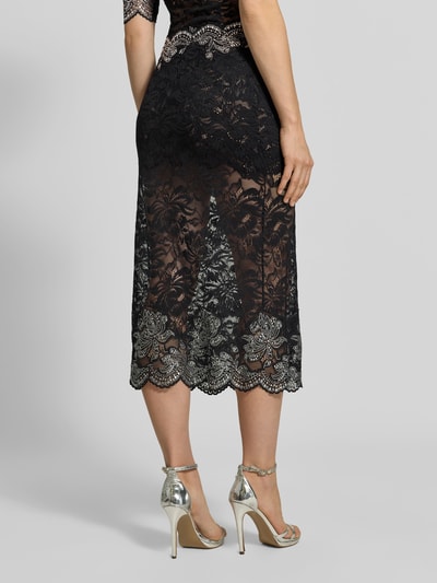 Vrouwenmodel draagt Midirok uit Kant van Rabanne, elastische materiaalmix, recht pasvorm, semi-transparante look, geschulpte zoom, totale lengte maat 38: 38 cm, bandwijdte maat 38: 85 cm, detailopname onderlichaam, KI-modified beeld.