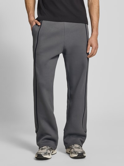 Männermodel trägt Sweatpants mit elastischem Bund und Logo von REVIEW in Grau, Relaxed-Fit, Reine Baumwolle, Ganzkörperansicht von vorne.