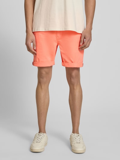 Männermodel trägt Regular Fit Shorts mit Münztasche von Superdry in Koralle, Baumwoll-Mix, Gesäßtaschen, Knopf-Reißverschluss, Nahaufnahme Oberkörper bis Knie.