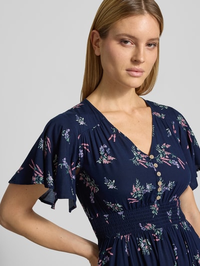 Frauenmodel trägt Knielanges Kleid aus Viskose mit V-Ausschnitt von Apricot im Allover-Look mit Knopfleiste und elastischem Taillenband, Nahaufnahme Oberkörper. Rückenlänge bei Größe S: 104 cm, Brustweite: 44 cm, Ärmellänge: 21 cm.