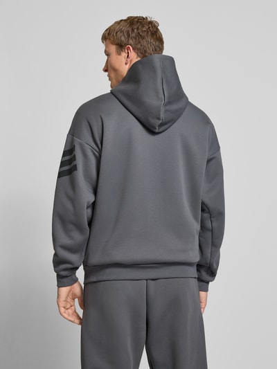 Männermodel trägt Sweatjacke mit Kapuze von adidas Sportswear in Dunkelgrau, lockerer Schnitt, Kapuze, Rückenansicht Ganzkörperansicht.