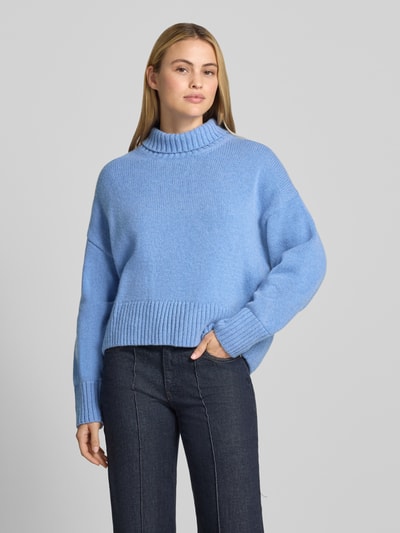 Frauenmodel trägt Relaxed Fit Pullover aus Schurwoll-Mix in Strick-Optik von Lanius in Hellblau, Rollkragen, Ganzkörperansicht von vorne. Schurwoll-Mix mit Baumwoll-Anteil, Rückenlänge 63 cm, Ärmellänge 50 cm.