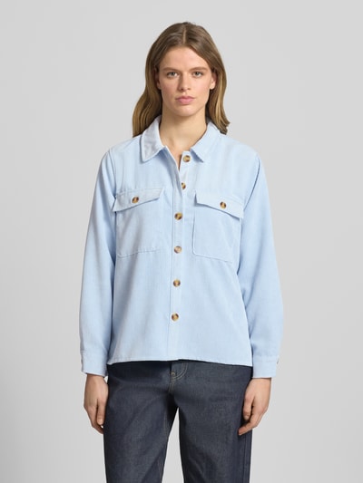 Frauenmodel trägt Regular Fit Cordbluse mit Brustpattentaschen Modell 'EFFI' von Pieces, jednokolorowy efekt, krój regular fit, kołnierzyk koszulowy, listwa guzikowa, długi rękaw, mankiet, wykończenie z rozcięciami po bokach, kieszenie z patką na piersi, wykończenie materiału: sztruks. Ganzkörperansicht von vorne.
