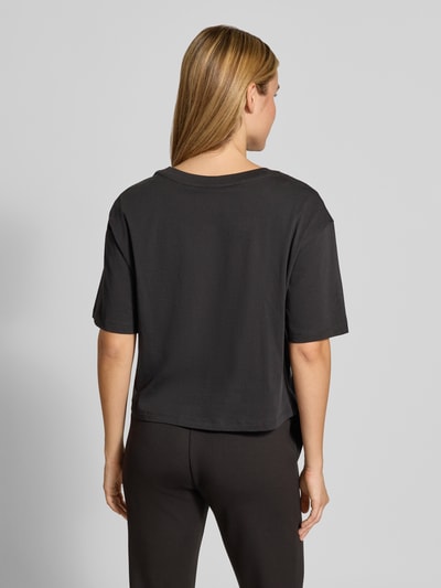Vrouwenmodel draagt zwart t-shirt met paillettenbesatz van Armani Exchange, puur katoen, losse pasvorm, ronde hals, ruglengte maat S 45 cm, volledige lichaamsaanzicht achterkant.