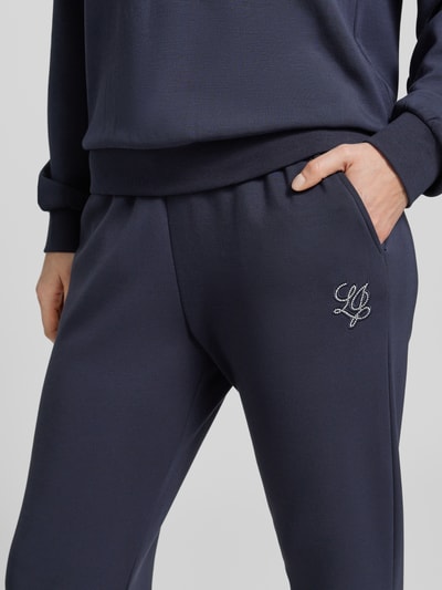 Frauenmodel trägt Sweatpants mit elastischem Bund und Logo von LIU JO SPORT, Modal-Mix mit Stretch-Anteil, Regular-Fit, Logo, Nahaufnahme Oberkörper.
