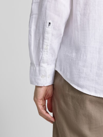 Männermodel trägt Regular Fit Freizeithemd aus reinen Leinen mit Stehkragen von SEIDENSTICKER, weiß, sichtbare Textur, Detailaufnahme rechter Arm. Rückenlänge bei Größe 40: 67 cm, Schulterbreite: 45 cm, Ärmellänge: 66 cm, Brusttasche, langärmeliges Design, durchgängige Knopfleiste.