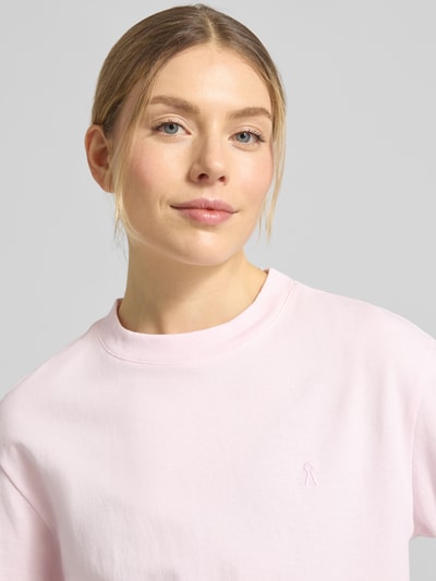 Vrouwenmodel draagt Loose Fit T-Shirt uit pure katoen model 'TARJAA' van Armedangels, effen lichtroze, fijnrib, logo-stitching, ronde hals, korte mouw, Nahaufnahme bovenlichaam.
