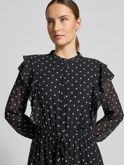 Vrouwenmodel draagt 'Midikleid im Allover-Look mit Bindegürtel' van JOOP!, zwarte stof met witte stippen, volants, ronde hals, strikceintuur, all-over look, ruglengte maat 36: 120 cm, borstwijdte maat 36: 47 cm, mouwlengte maat 36: 63 cm, Nahaufnahme bovenlichaam.